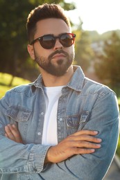 Handsome man in sunglasses outdoors on sunny day