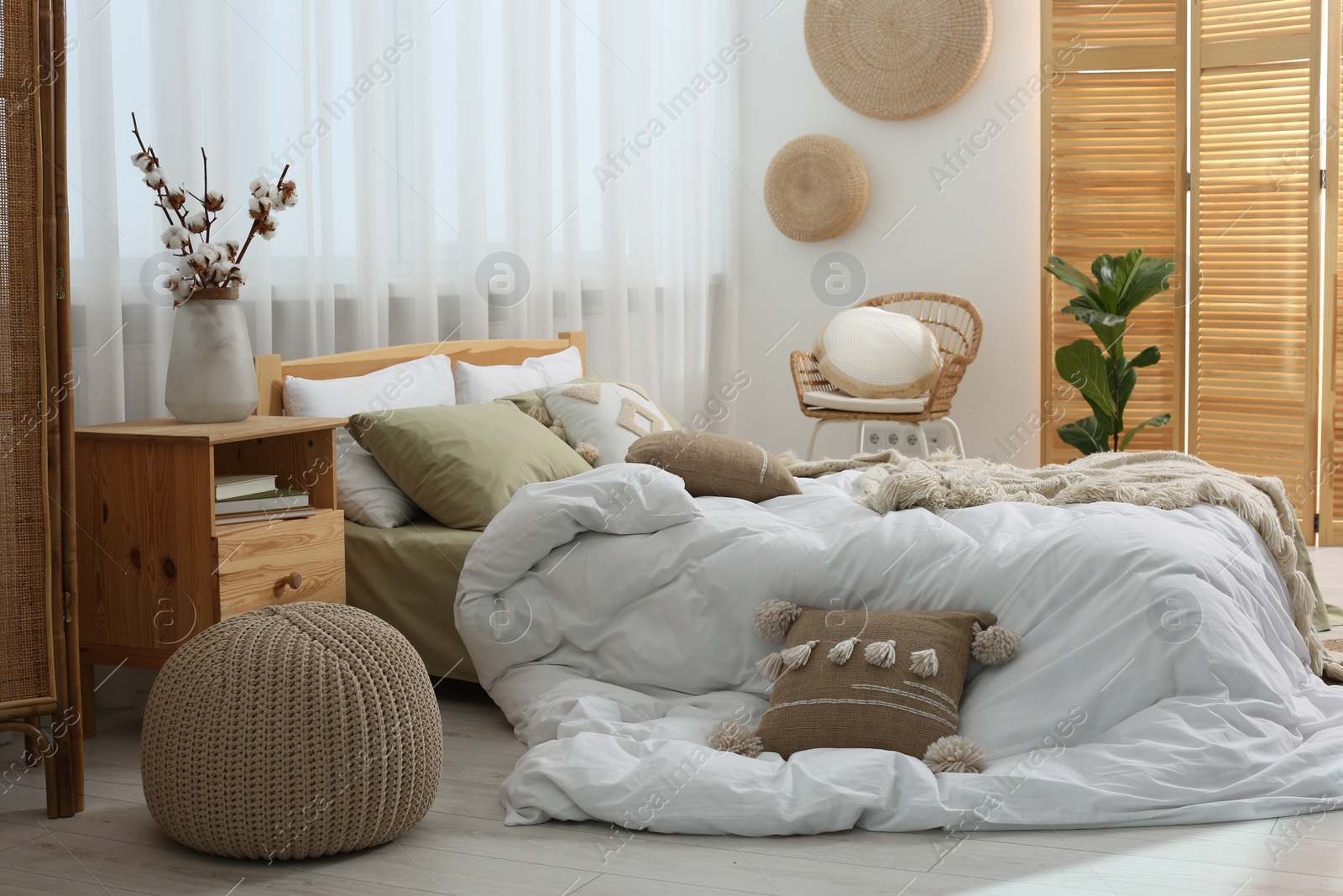 Photo of Large comfortable bed with soft pillows, duvet and blanket in room. Home textile