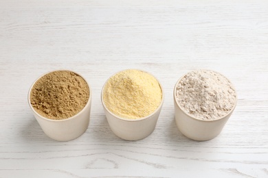 Photo of Bowls with different types of flour on white wooden background