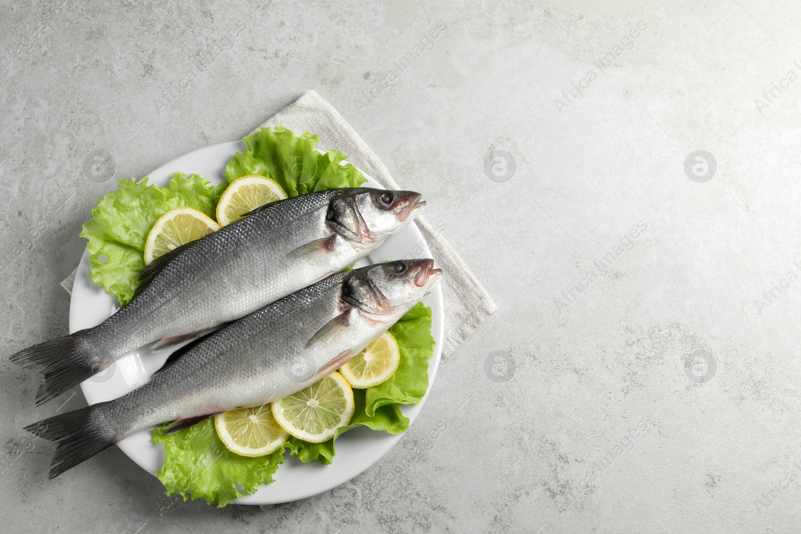Photo of Tasty sea bass fish on grey textured table, top view. Space for text