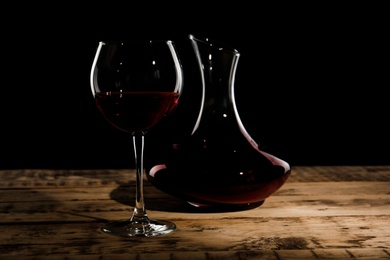 Elegant decanter and glass with red wine on table against dark background