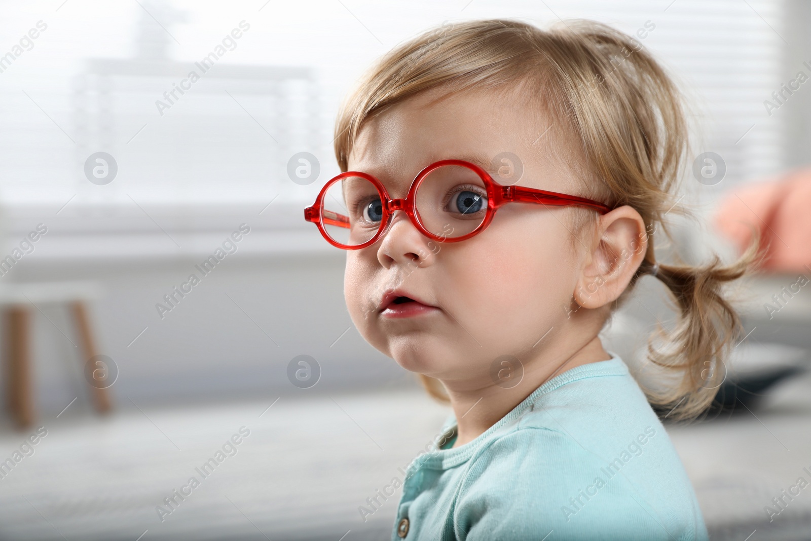 Photo of Cute little girl in glasses at home. Space for text