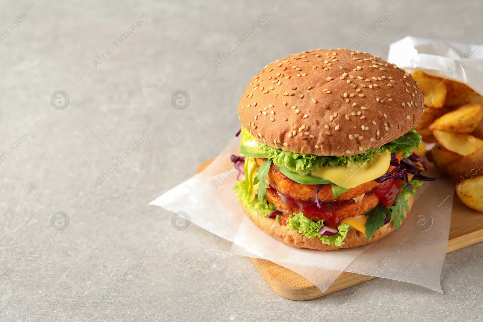 Photo of Vegan burger with carrot patties and fried potato served on grey table. Space for text