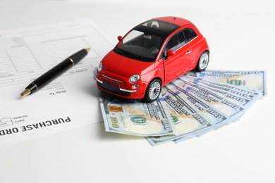 Toy car, money and insurance contract on table