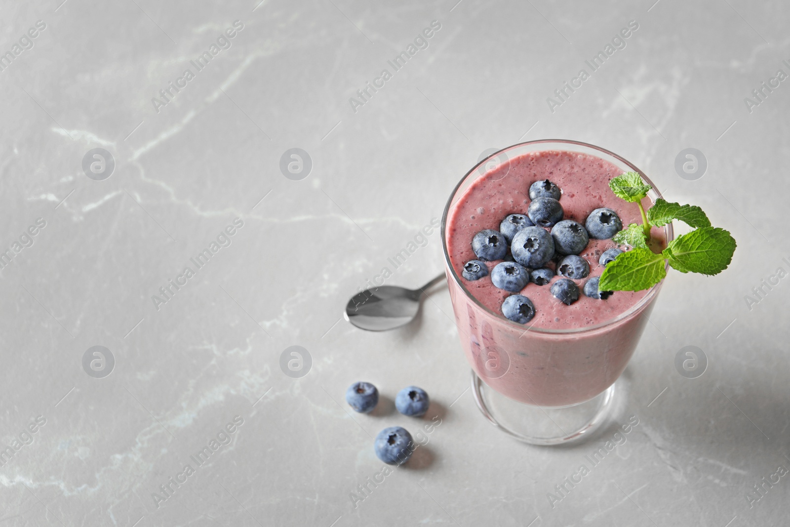 Photo of Glass with blueberry smoothie on light background. Space for text