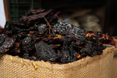 Pile of dried black ancho chiles in burlap, closeup