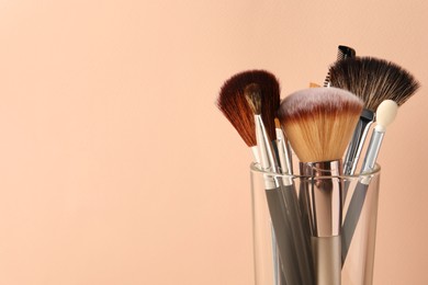 Photo of Set of professional makeup brushes on beige background. Space for text