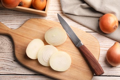 Photo of Whole and sliced onions on white wooden table, flat lay