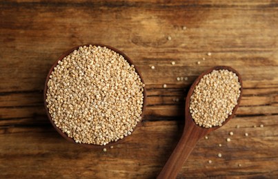 Photo of Bowl and spoon with white quinoa on wooden table, flat lay
