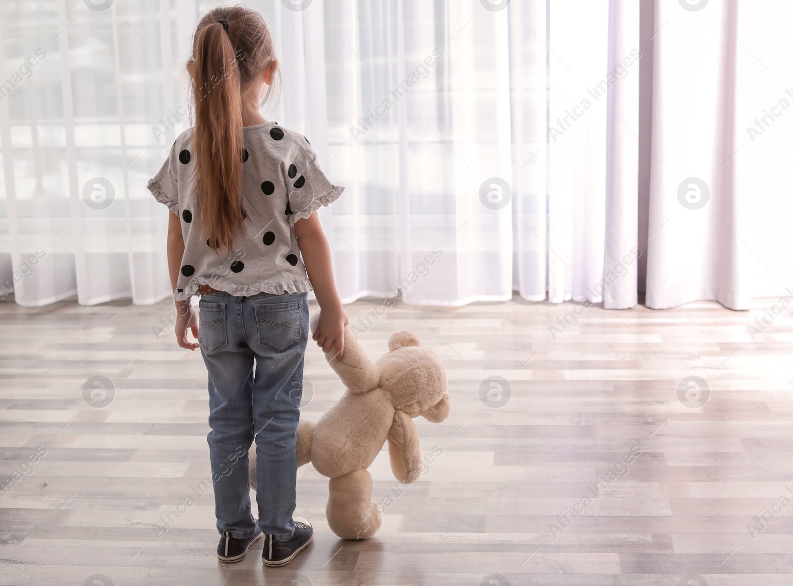 Photo of Lonely little girl with toy indoors. Autism concept