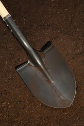 Photo of Metal shovel on fertile soil, top view. Gardening tool