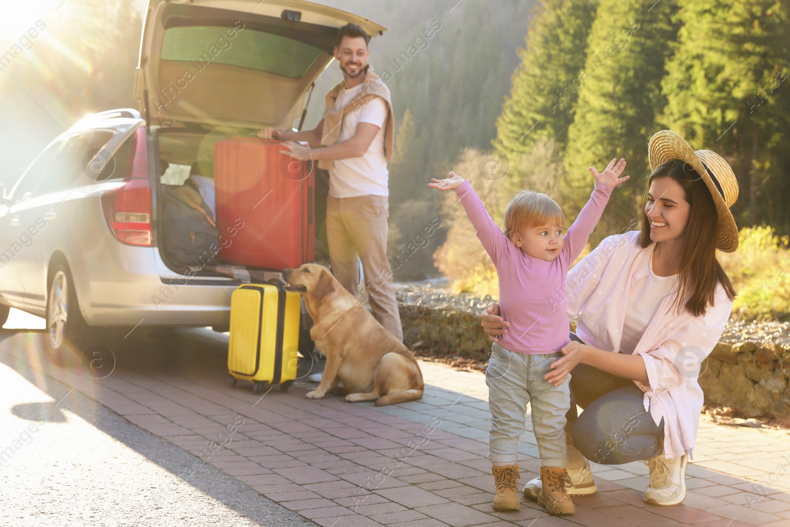 Photo of Mother with her daughter, man and dog near car outdoors. Family traveling with pet