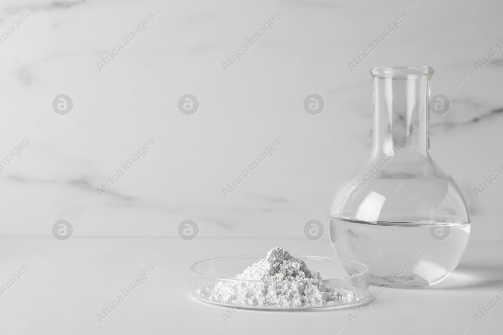 Photo of Petri dish with calcium carbonate powder and laboratory flask on white table. Space for text