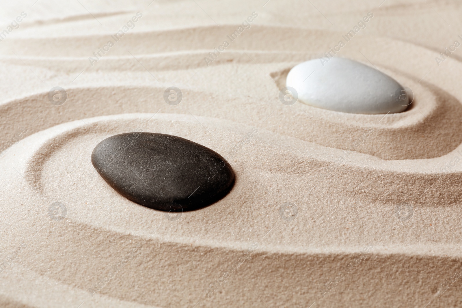 Photo of Zen garden stones on sand with pattern. Meditation and harmony