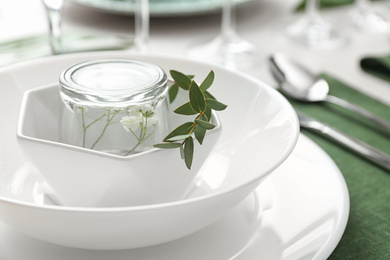 Photo of Stylish tableware with green leaves on table, closeup. Festive setting