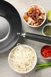 Photo of Flat lay composition with black wok, spices and products on grey textured table