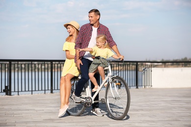 Photo of Happy family riding bicycle outdoors on sunny day