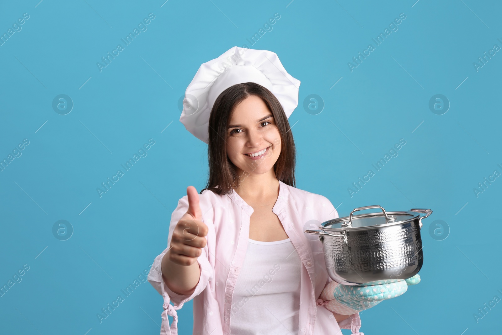 Photo of Happy young woman with cooking pot on light blue background