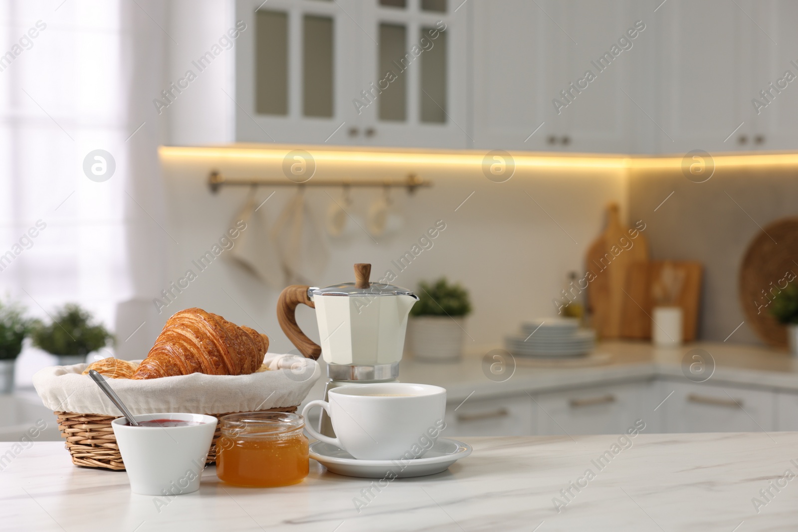 Photo of Breakfast served in kitchen. Fresh croissants, jam, honey and coffee on white table, space for text