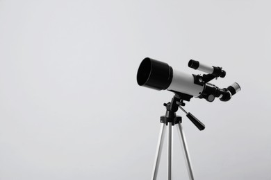 Photo of Tripod with modern telescope on light grey background, closeup. Space for text