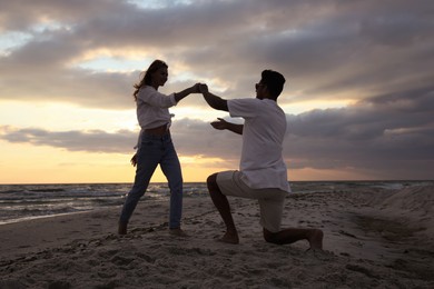 Happy couple dancing on beach at sunset