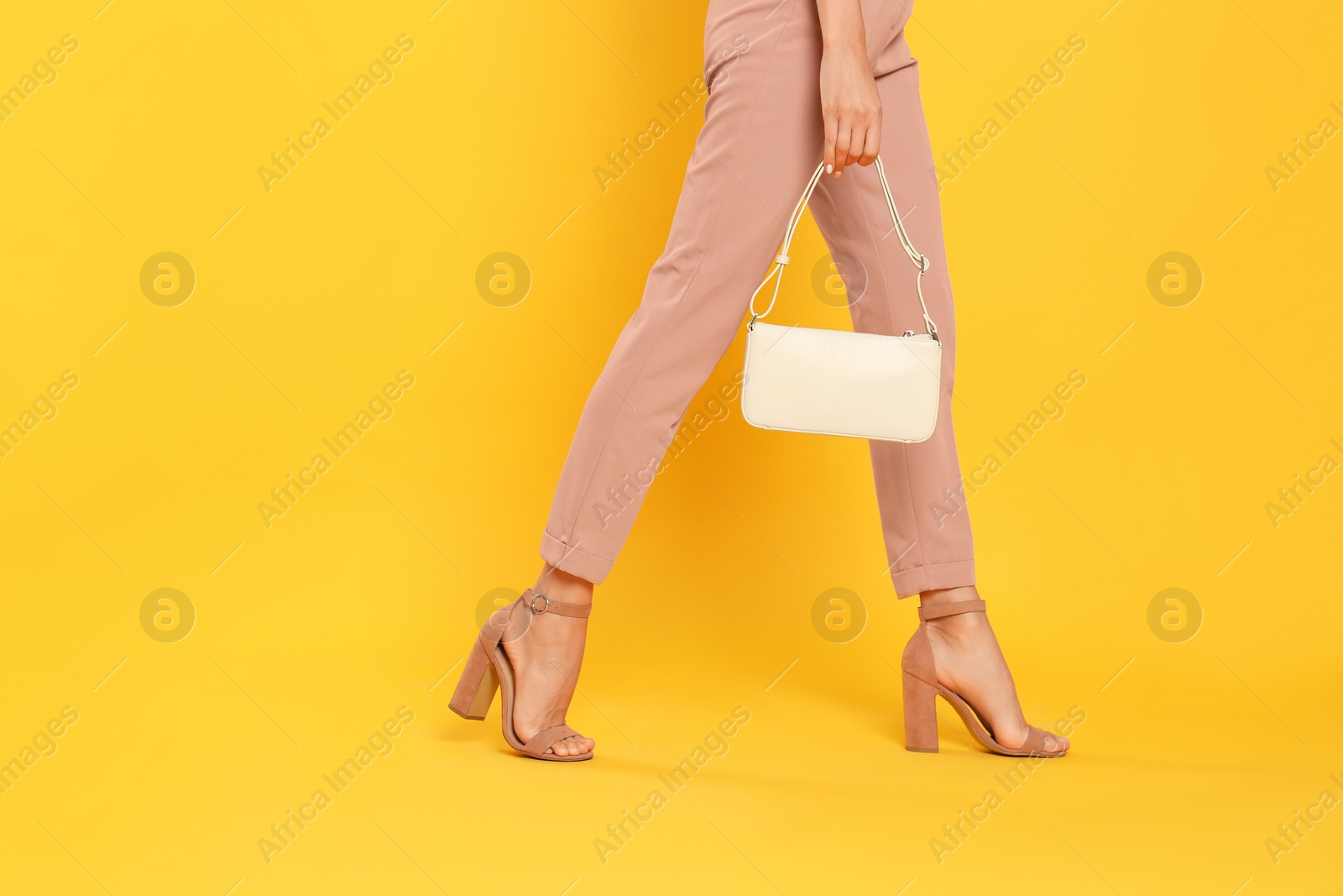 Photo of Woman with stylish bag on yellow background, closeup