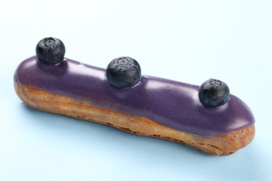 Photo of Delicious eclair covered with glaze on light blue background