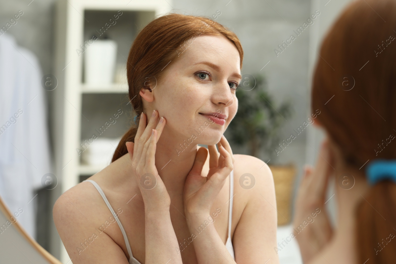 Photo of Beautiful woman with freckles near mirror in bathroom