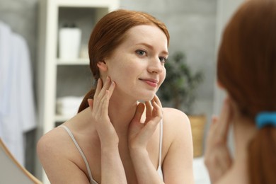 Beautiful woman with freckles near mirror in bathroom