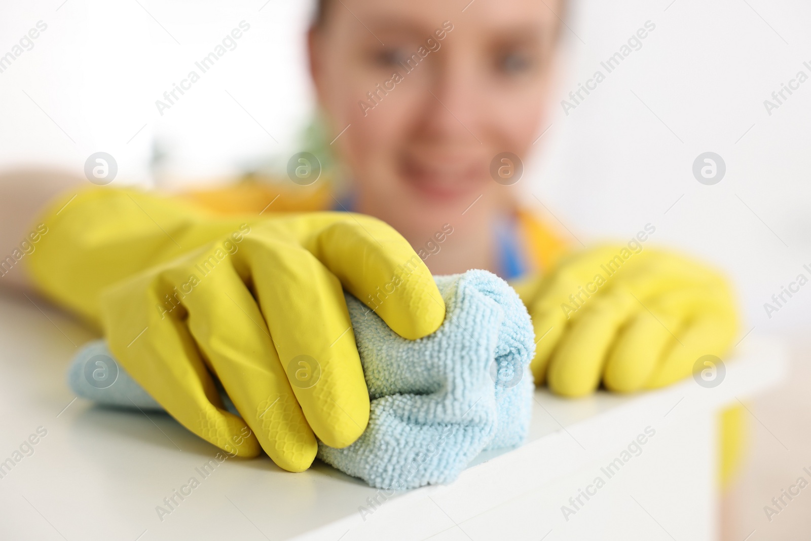 Photo of Woman cleaning table with rag at home, selective focus