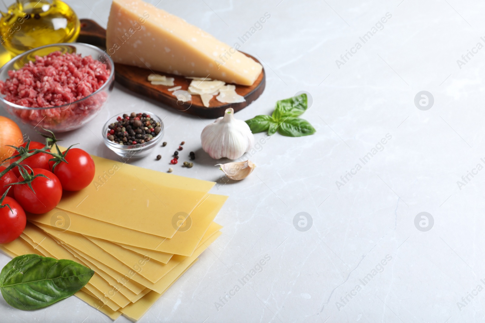 Photo of Fresh ingredients for lasagna on light grey marble table. Space for text