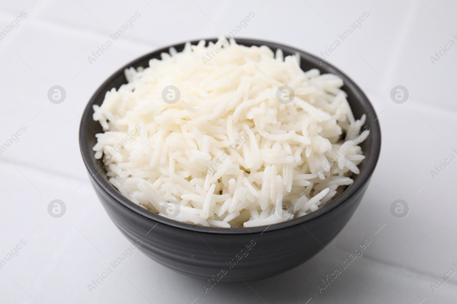 Photo of Bowl of delicious rice on white table, closeup