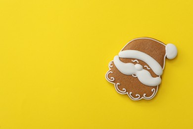 Photo of Christmas Santa Claus shaped gingerbread cookie on yellow background, top view. Space for text