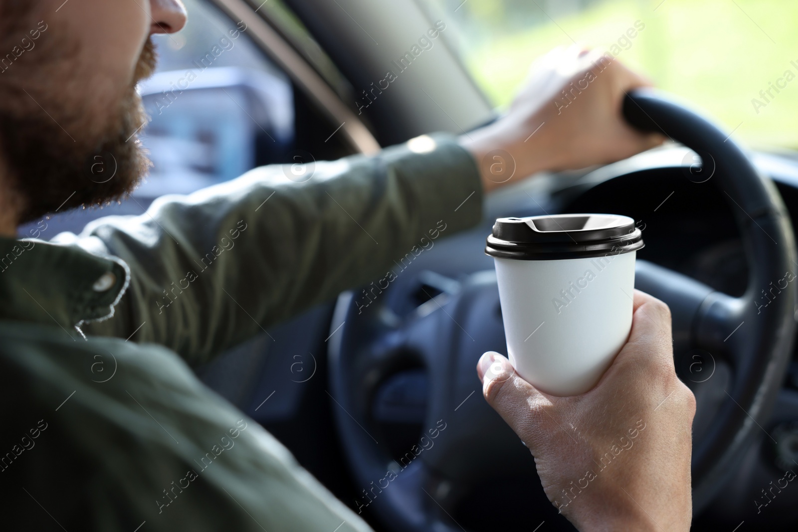 Photo of Coffee to go. Man with paper cup of drink in car, closeup