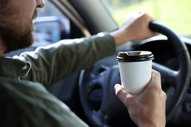 Coffee to go. Man with paper cup of drink in car, closeup