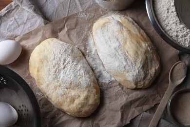 Photo of Raw dough, eggs and flour on parchment paper, flat lay. Cooking ciabatta