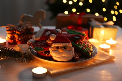 Photo of Decorated cookies on white table against blurred Christmas lights