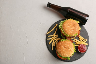 Photo of Flat lay composition with burgers, french fries and bottle on grey background. Space for text