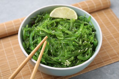 Photo of Tasty seaweed salad in bowl served on gray table, closeup