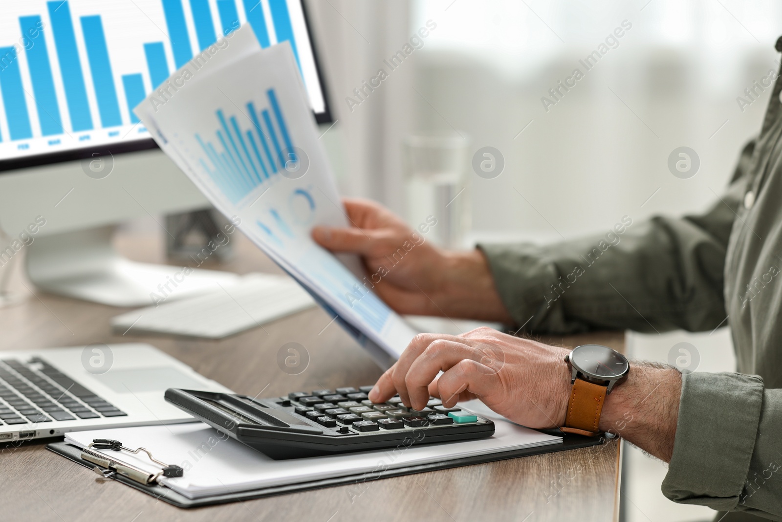 Photo of Professional accountant using calculator at wooden desk in office, closeup