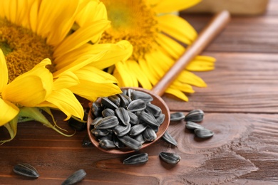 Photo of Spoon with sunflower seeds on wooden table, closeup