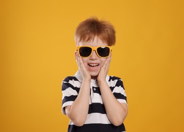 Photo of Cute little boy with sunglasses on yellow background