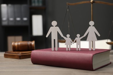 Photo of Family law. Figure of parents with children, book, scales of justice and gavel on wooden table