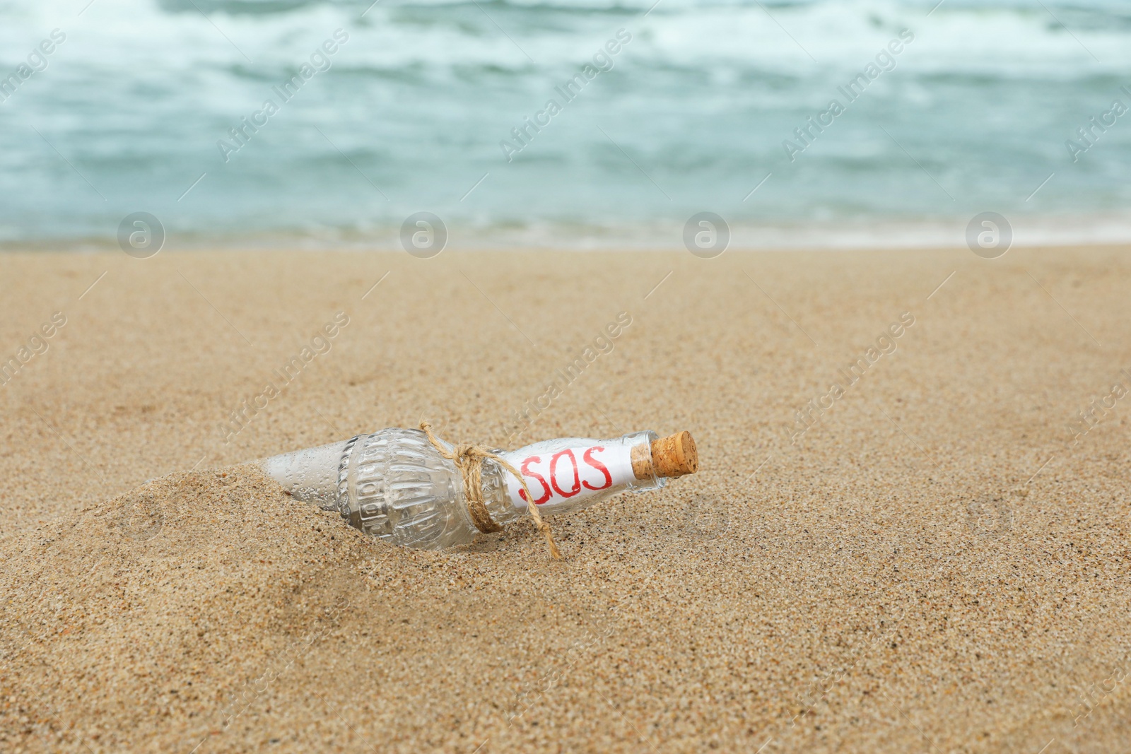 Photo of Glass bottle with SOS message on sand near sea