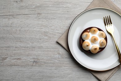 Delicious salted caramel chocolate tart with meringue served on light beige wooden table, top view. Space for text