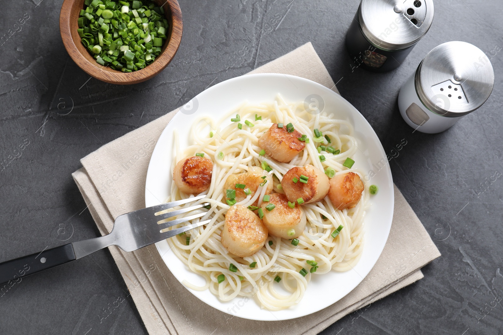 Photo of Delicious scallop pasta with green onion served on grey table, flat lay