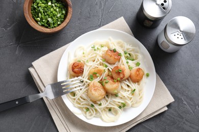 Delicious scallop pasta with green onion served on grey table, flat lay