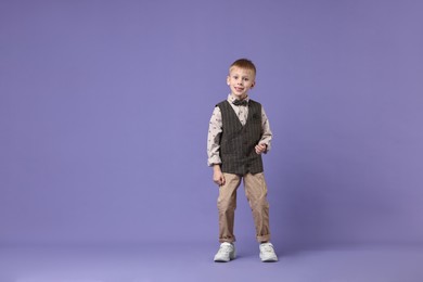 Photo of Happy little boy dancing on violet background. Space for text