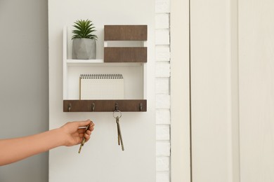 Photo of Woman taking keys from hanger in hallway, closeup