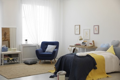 Photo of Modern teenager's room interior with bed and armchair